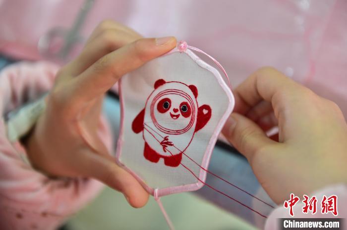 圖為一名小學(xué)生正在繡制2022年北京冬奧會(huì)吉祥物“冰墩墩”形象?！∮髟屏?攝