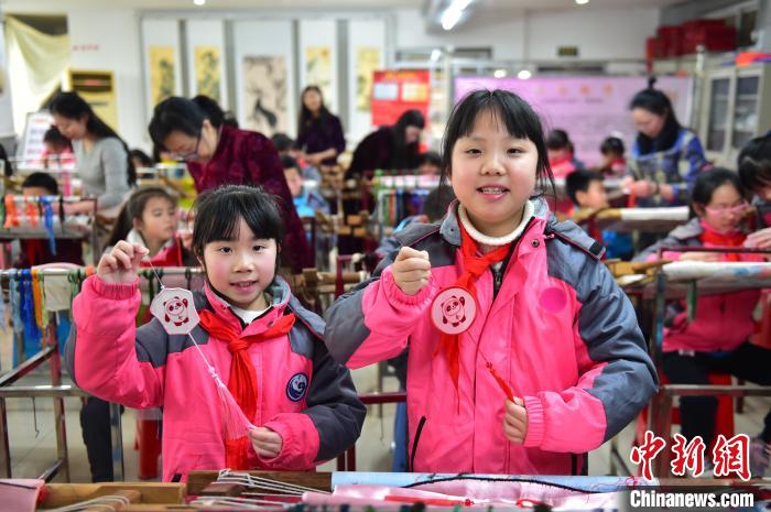 圖為小學(xué)生展示繡制好的2022年北京冬奧會(huì)吉祥物“冰墩墩”形象。　喻云亮 攝