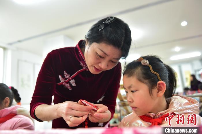 江西省級(jí)非遺豫章繡傳承人手把手指導(dǎo)小學(xué)生繡制2022年北京冬奧會(huì)吉祥物“冰墩墩”形象。　喻云亮 攝