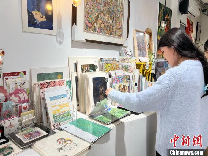 圖為藝術品商店內(nèi)，顧客挑選插畫作品?！＄婌?攝