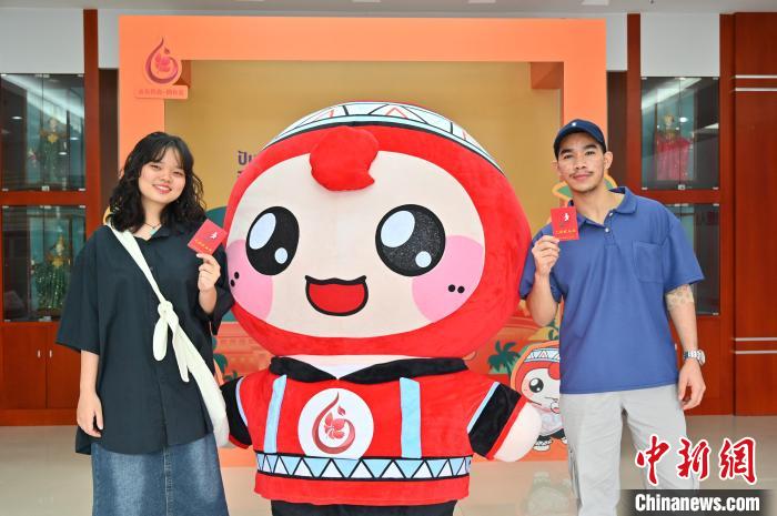 圖為泰國(guó)留學(xué)生手持獻(xiàn)血證與人偶合影。　俞靖 攝