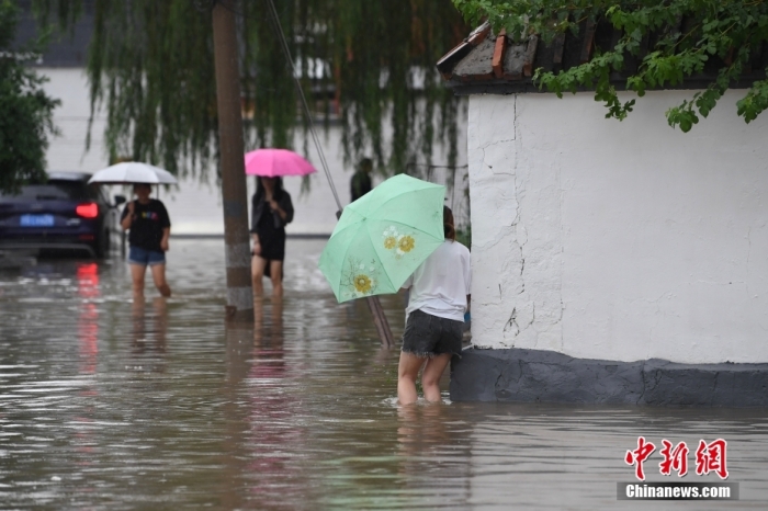 7月31日，市民行走在雨中的北京房山區(qū)瓦窯頭村。北京市氣象臺當(dāng)日10時發(fā)布分區(qū)域暴雨紅色預(yù)警信號。北京市水文總站發(fā)布洪水紅色預(yù)警，預(yù)計當(dāng)日12時至14時，房山區(qū)大石河流域?qū)⒊霈F(xiàn)紅色預(yù)警標(biāo)準(zhǔn)洪水。<a target='_blank' href='/'><p  align=