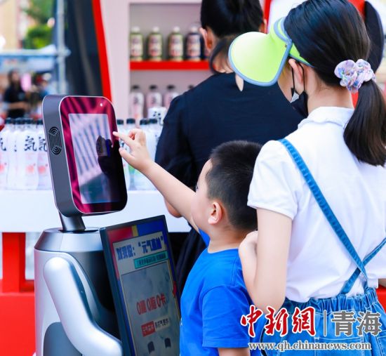 圖為一名小朋友正在和機(jī)器人“志愿者”進(jìn)行互動。 沐聞 攝