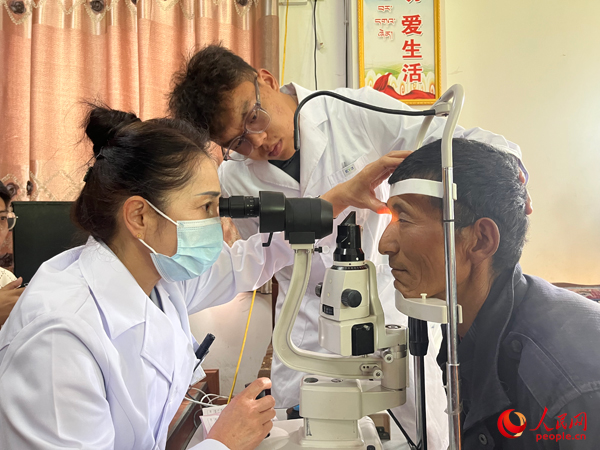 王紅英（左）和團隊成員為達熱村村民檢查眼睛。人民網記者 杜燕飛攝