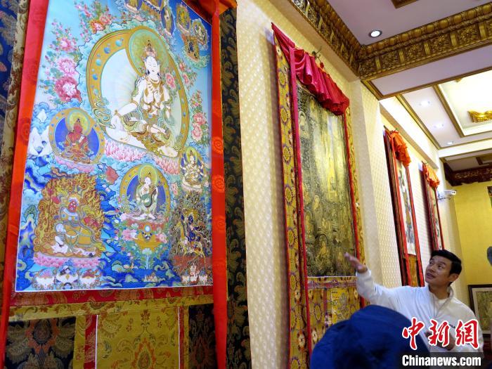 圖為完德尖措展示熱貢龍樹畫苑內(nèi)的唐卡?！?zhí)砀?攝