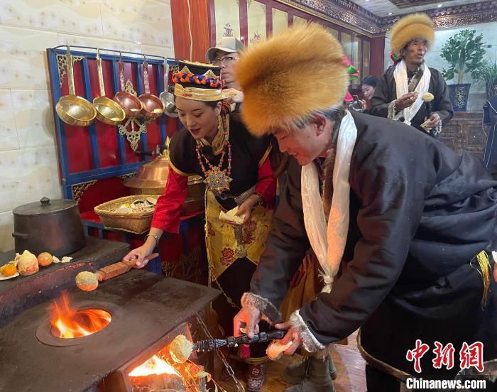 圖為人們在火上烤節(jié)日美食“結達”?！∪轿木?攝