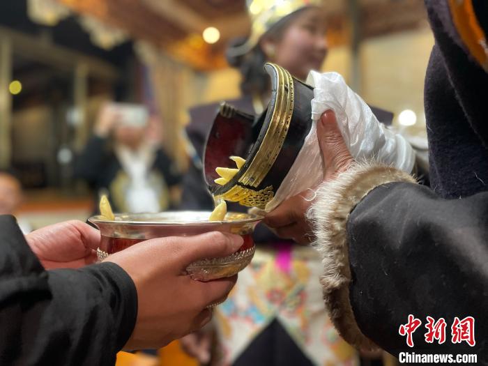 圖為主人在碗中斟滿青稞酒。　冉文娟 攝