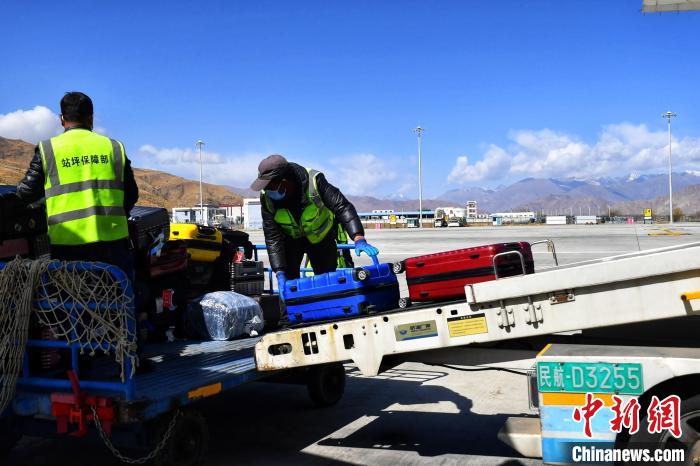 圖為機場工作人員傳送旅客行李箱?！≈芎?攝