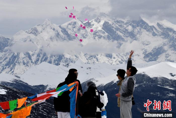 圖為5月14日，游客在西藏林芝色季拉山觀景臺(tái)拋灑“隆達(dá)”(風(fēng)馬旗，藏族民眾的一種祈福方式)?！±盍?攝