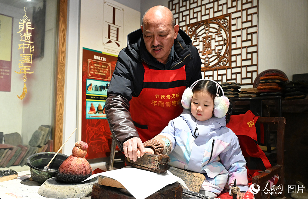 2025年1月27日，河南開封朱仙鎮(zhèn)木版年畫藝人尹國(guó)法指導(dǎo)小朋友研習(xí)年畫印制技藝。朱仙鎮(zhèn)木版年畫源自漢唐壁畫藝術(shù)，是中國(guó)木版年畫的鼻祖。2006年5月20日，朱仙鎮(zhèn)木版年畫經(jīng)國(guó)務(wù)院批準(zhǔn)列入第一批國(guó)家級(jí)非物質(zhì)文化遺產(chǎn)名錄。人民網(wǎng)記者 王玉興攝